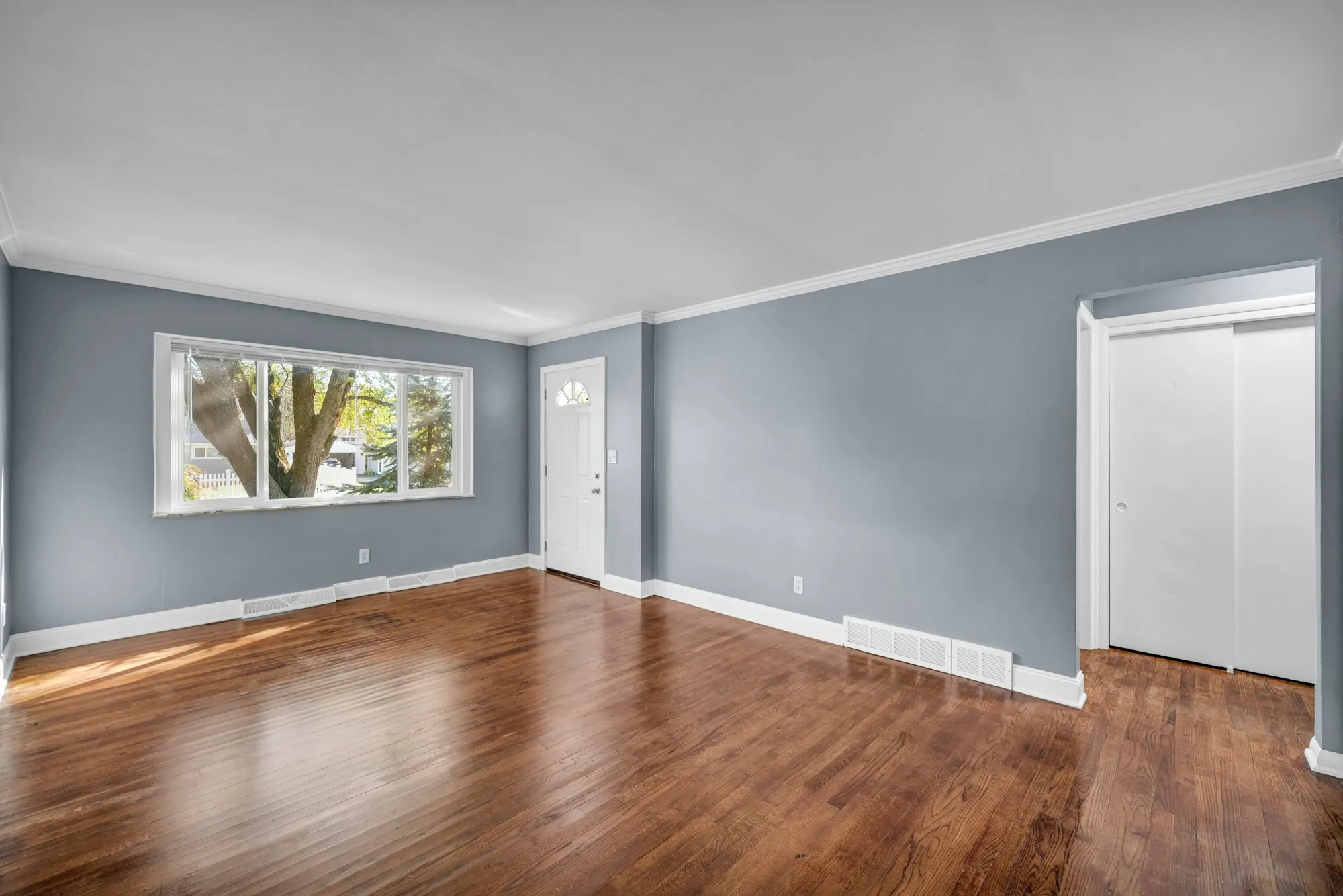 Living room with hardwood floors, grey walls and a large picture window